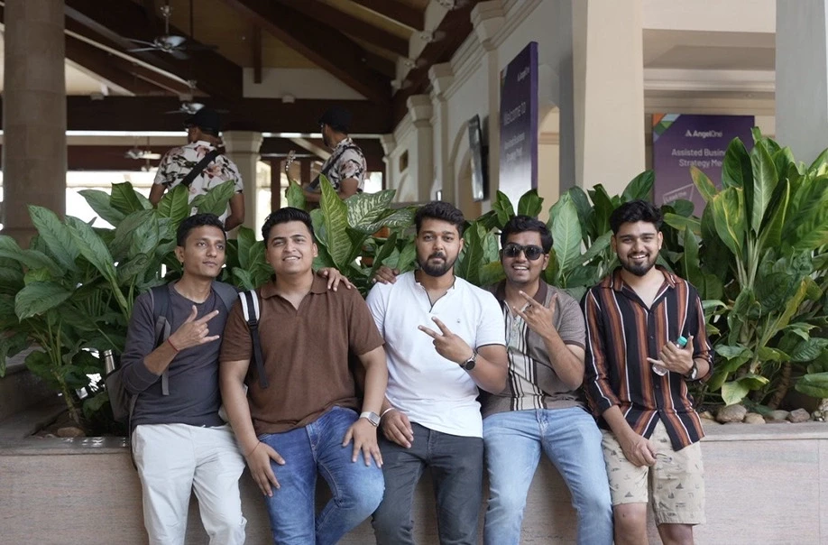 Five friends posing together, smiling, and making peace signs.