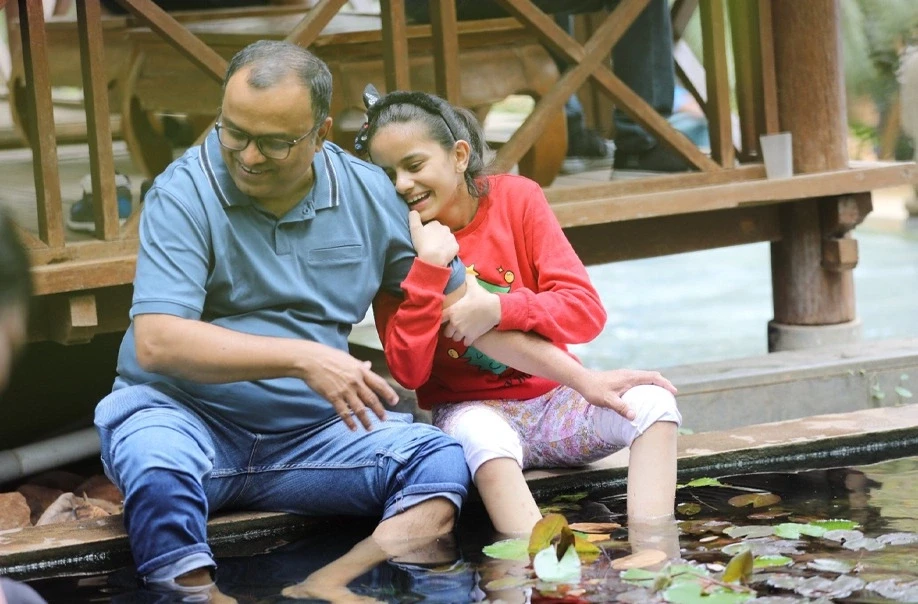 Father and daughter laughing by the pond