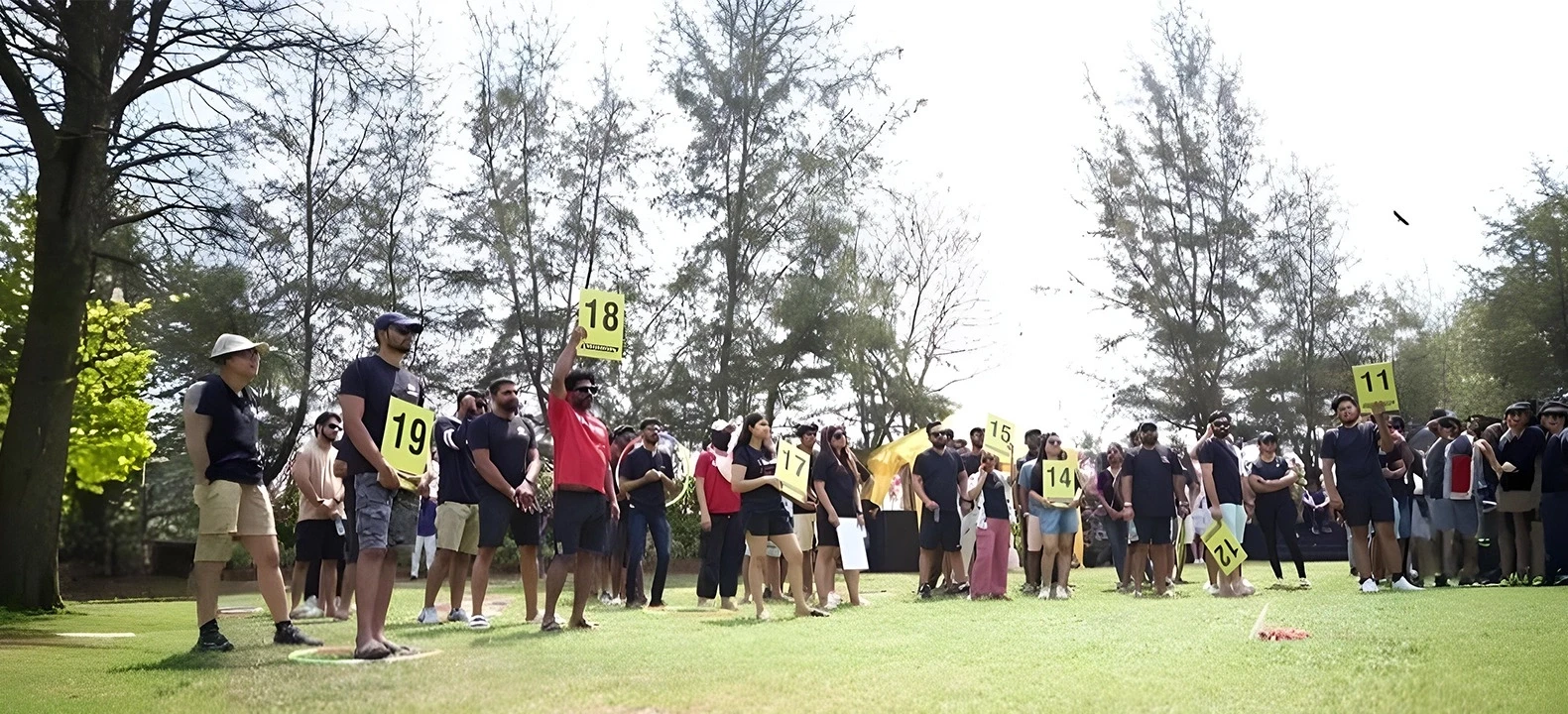 People standing on grass holding numbered signs outdoors.